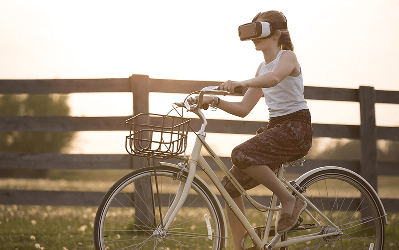 VR機を付けて自転車に乗る女性の画像